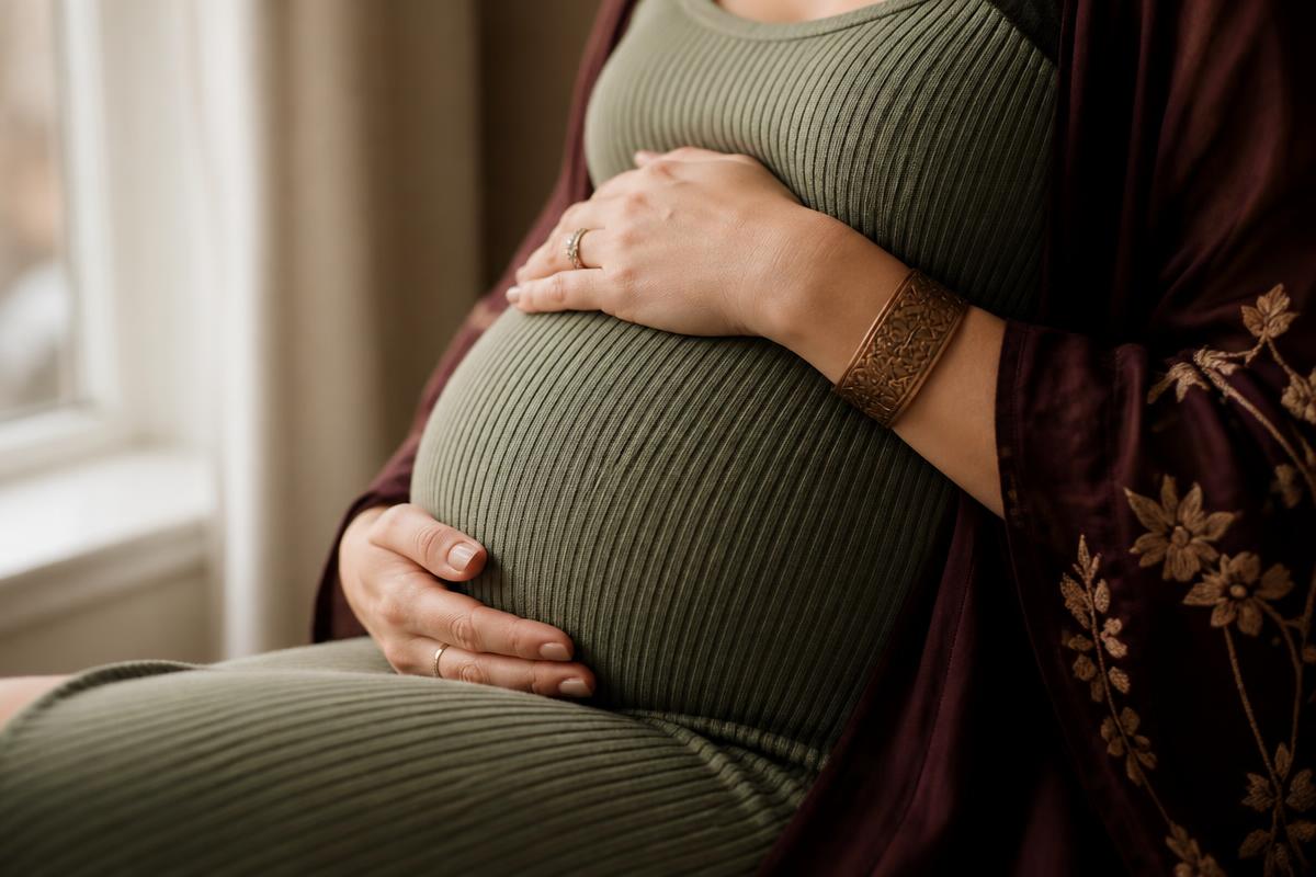 A pregnant woman gently resting her hands on her bump